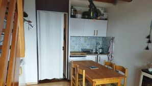 Una cocina compacta con una mesa y sillas de madera, un armario blanco y un salpicadero de azulejos.