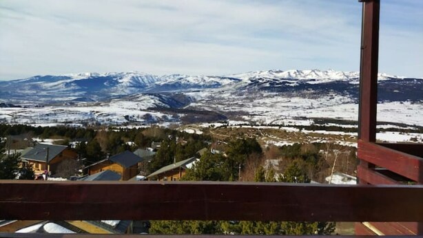 Paisaje montañoso con picos nevados y vista a un pueblo en la falda.