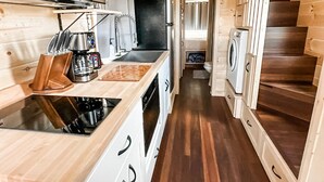 Une cuisine de taille réduite, avec des meubles de rangement en bois, un évier, une cuisinière et un four à micro-ondes.