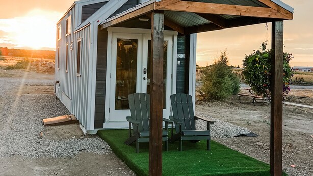Une petite cabane à un seul étage, dotée d’un porche couvert et de deux fauteuils Adirondack.