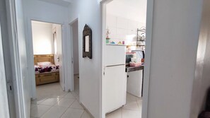 A narrow hallway leading to a bedroom and a kitchen area with a refrigerator and a microwave. - Appartement spacieux a agadir ensoleillé  (Agadir)