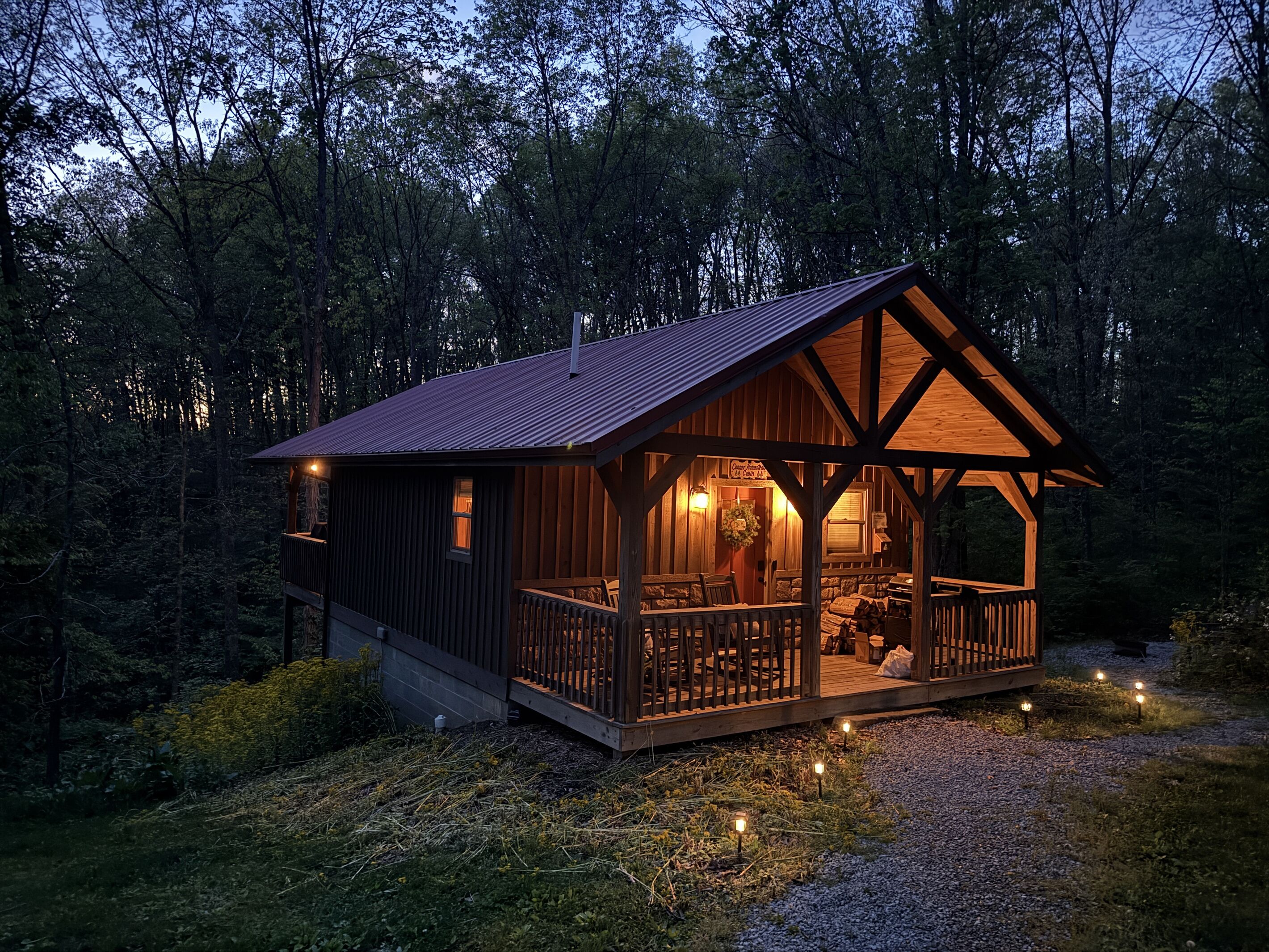 A cabin with a wooden exterior, a porch with seating, and a visible fireplace.