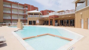 A hotel with a swimming pool, outdoor seating, and multiple balconies.