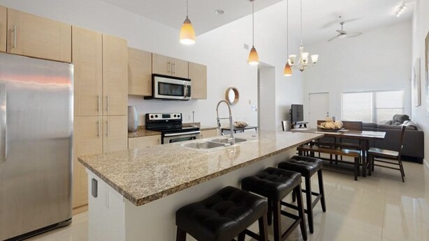 A modern kitchen with a central island, stainless steel appliances, and pendant lighting.