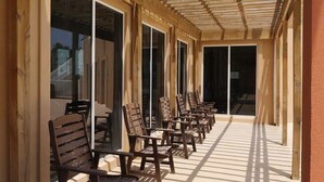 A covered outdoor seating area with wooden benches and large windows.