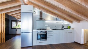 Une cuisine moderne dotée d’un four encastré, d’appareils électroménagers en acier inoxydable et de poutres en bois au plafond.