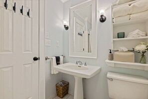 Ein Badezimmer mit Waschbecken, Toilette, Spiegel und Ablagefläche mit Handtüchern.