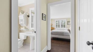 A bedroom with a bed, a bedside table, and a window with shutters.