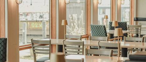 Un restaurant aux murs lambrés, doté de grandes fenêtres et d’un éclairage moderne.