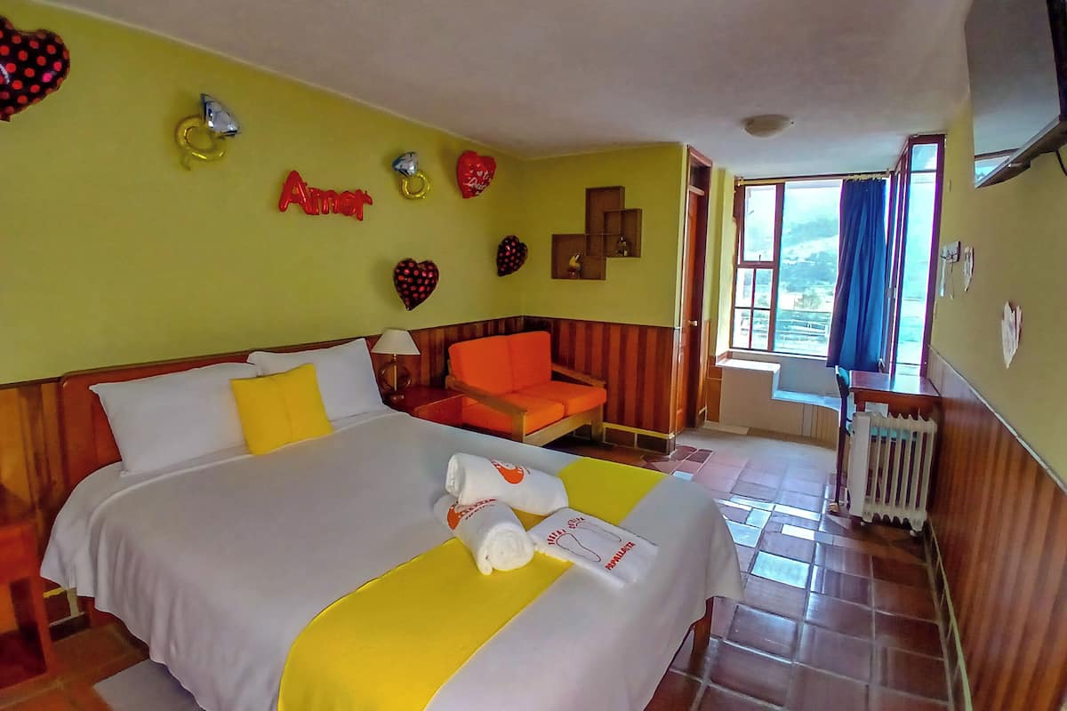 Une chambre d’hôtel avec un lit, une chaise, une fenêtre et des éléments décoratifs sur le mur.
