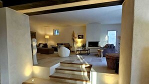 A spacious living area with a staircase leading to another room, a sofa, a lamp, and a television.