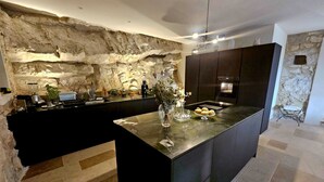 A modern kitchen with a central island, stone wall backsplash, and contemporary appliances.