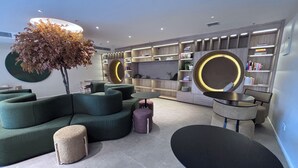 A modern lounge area with a green sofa, round tables, and a bookshelf. - Modern Enaki Resort Apartment (Nairobi)