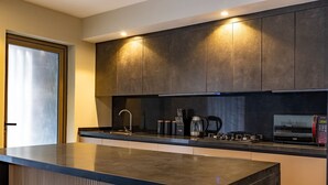 A modern kitchen with dark cabinetry, a stainless steel sink, a coffee maker, and a microwave. - Modern Enaki Resort Apartment (Nairobi)