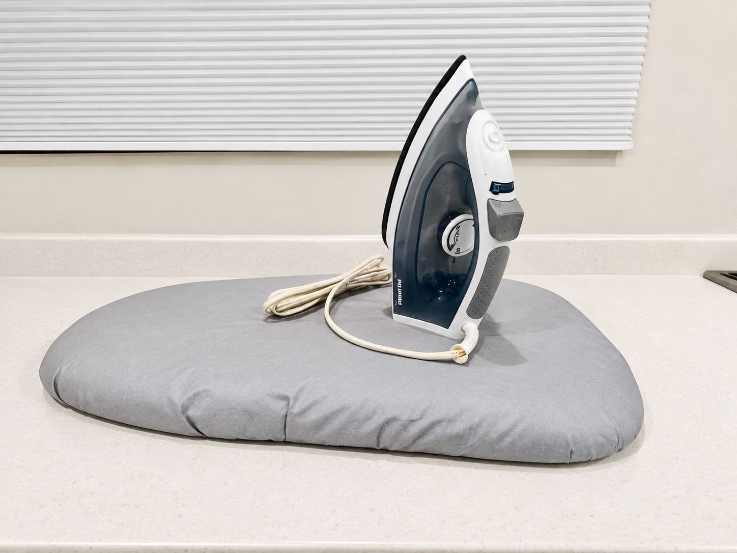 An iron on a gray cushion on a countertop.