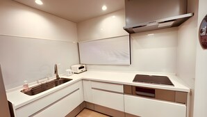 A modern kitchen with white cabinets, a stainless steel sink, a toaster, and a range hood. - Eternity Marina HOUSE Onjuku (Onjuku)