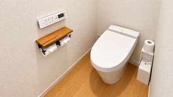 A small, modern bathroom with a toilet, a toilet paper holder, and a bidet.