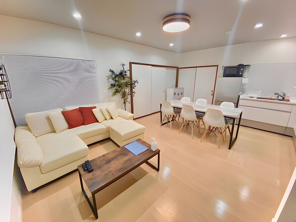 Ein modernes Wohnzimmer mit einem Ecksofa, einem Couchtisch und einem Essbereich mit Stühlen und Tisch.