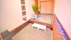 A spacious hallway with a tiled floor, a potted plant, a bench, and a door with a sliding mechanism. - Eternity Marina HOUSE Onjuku (Onjuku)