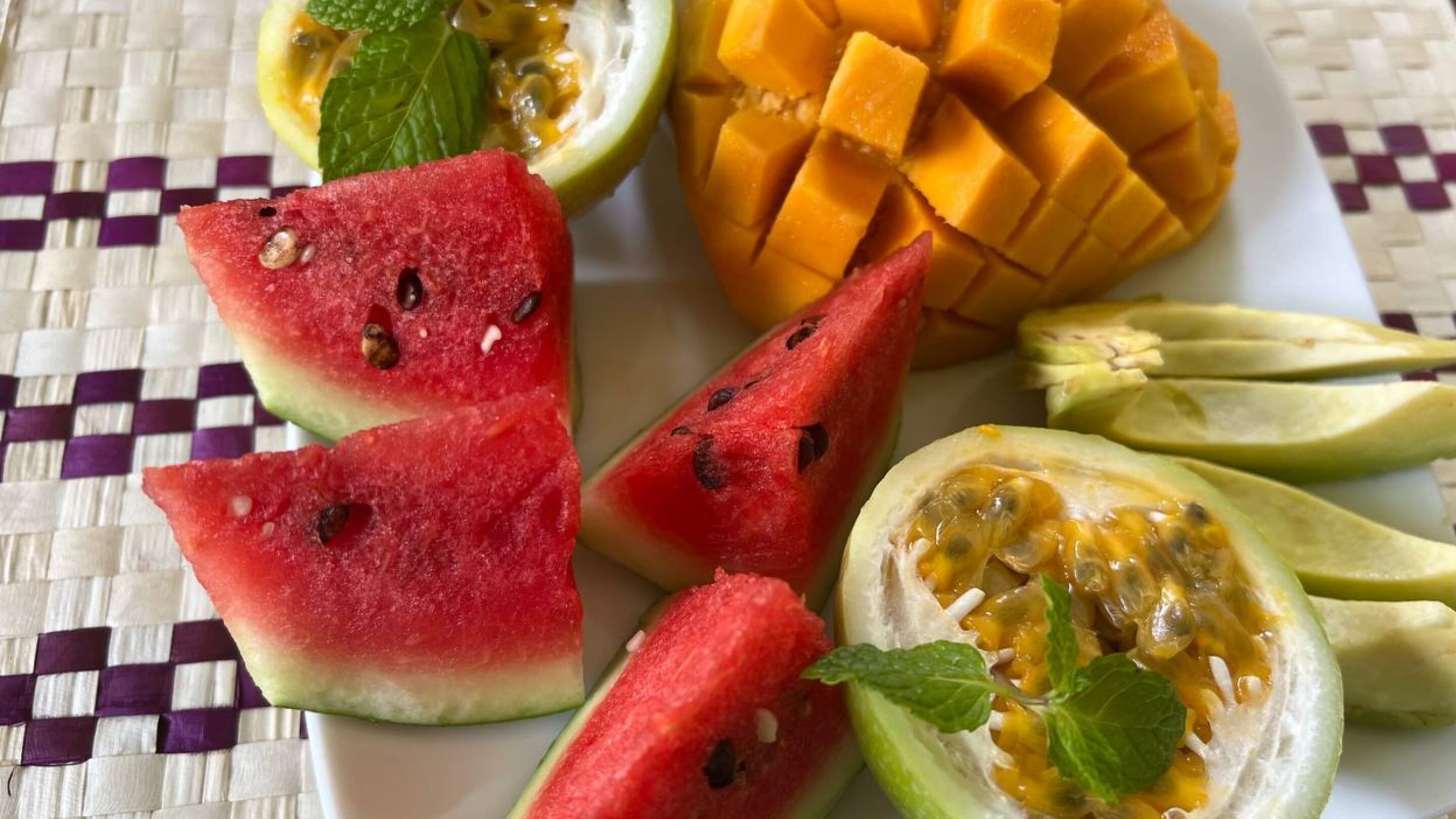 A plate with sliced watermelon, mango, and passion fruit.