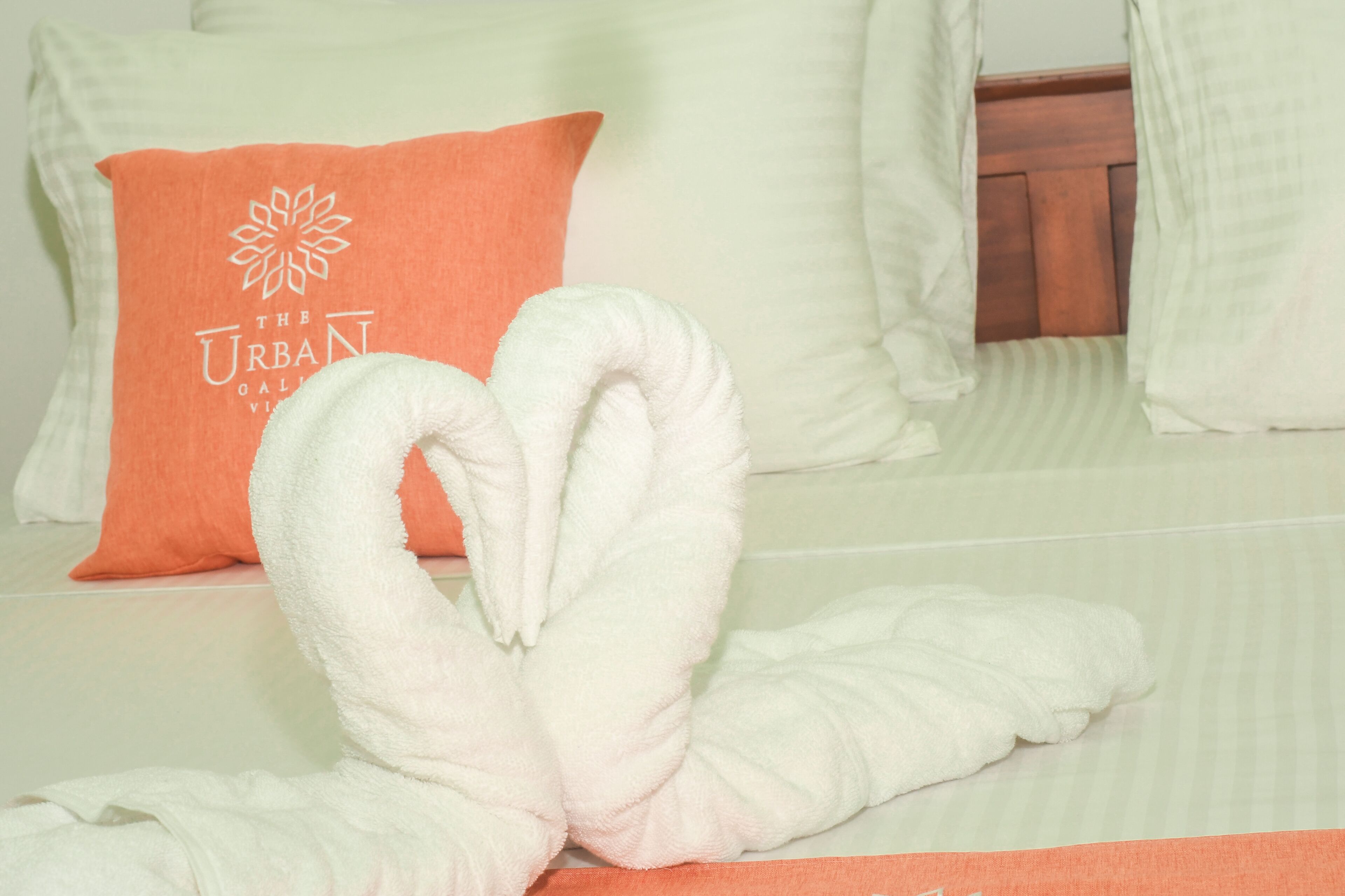 A bed with white pillows, one of which has a logo and text.