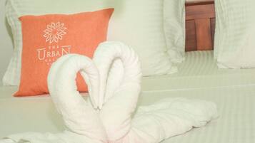 A bed with white pillows, one of which has a logo and text.