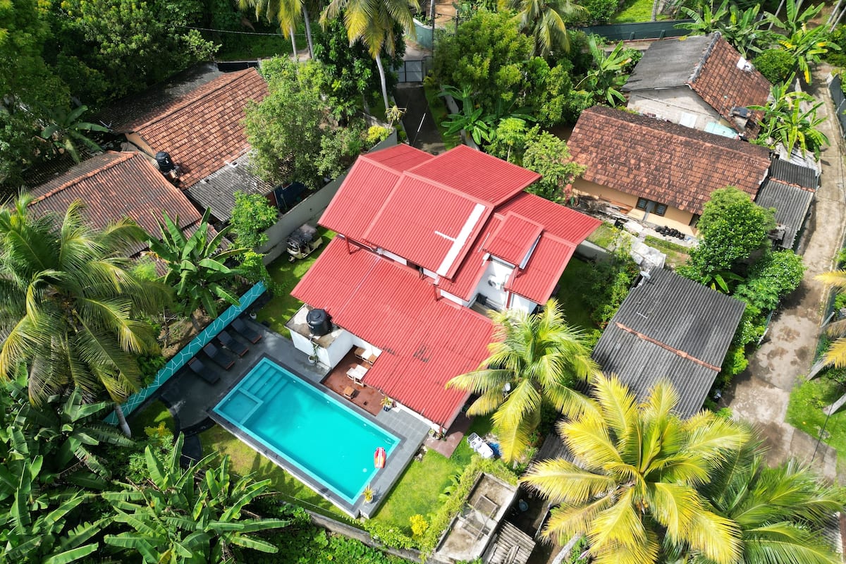 Vista aérea de una zona residencial con varias casas, una piscina y abundante vegetación.