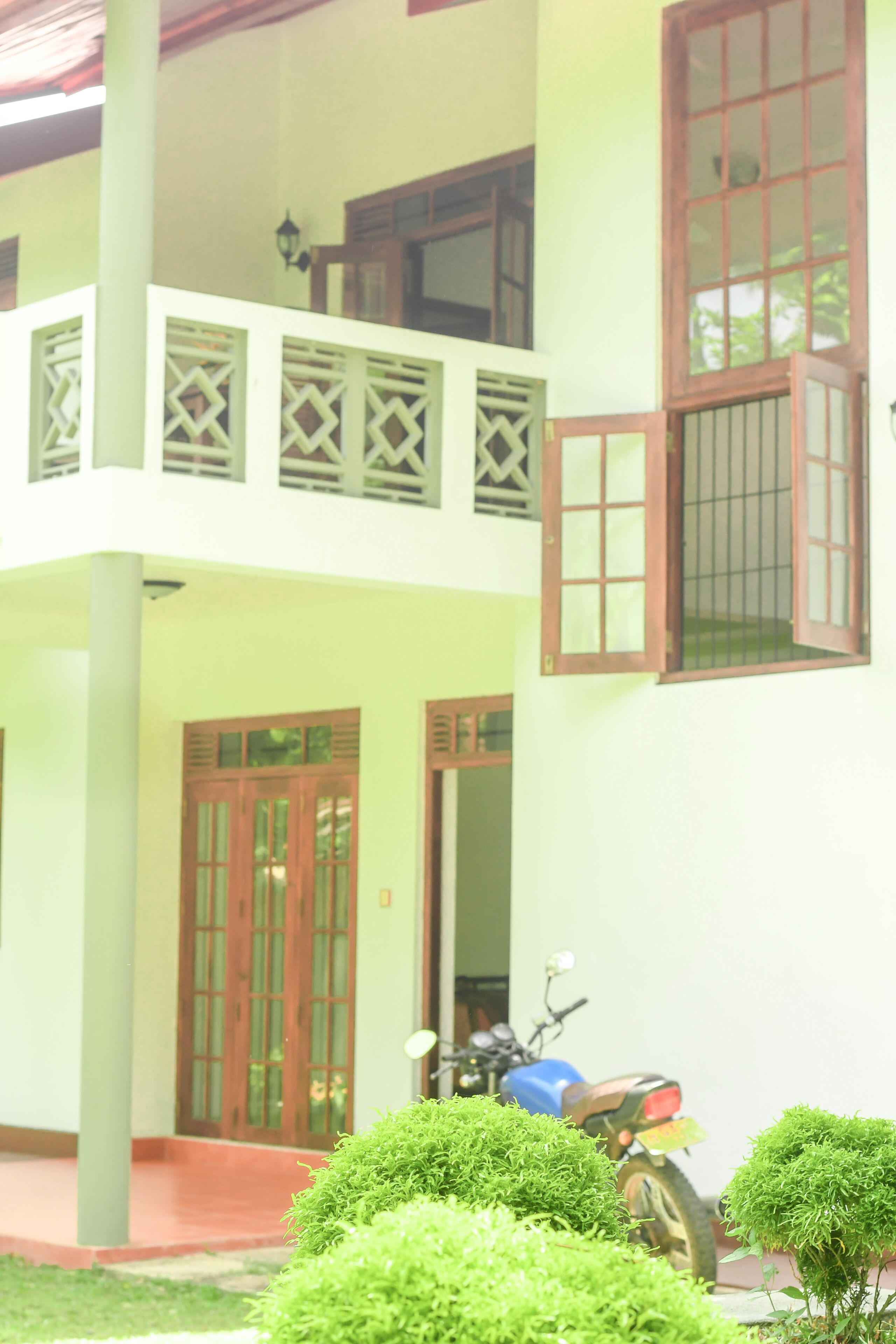 A two-story building with a balcony, wooden doors, and a parked motorcycle.