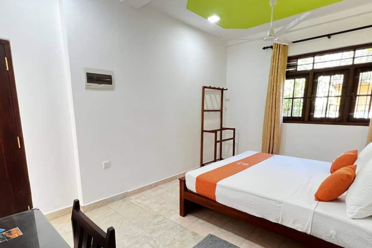 Un dormitorio con cama, escritorio, silla, ventana con cortinas y ventilador de techo.