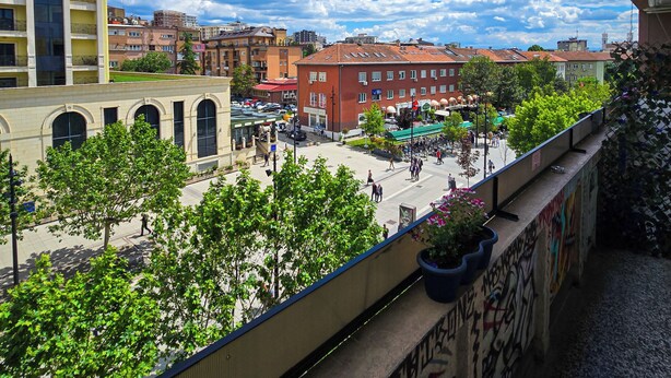A balcony with a view of a city street, buildings, and a clear sky. - Urban Cozy Retreat (Pristina)