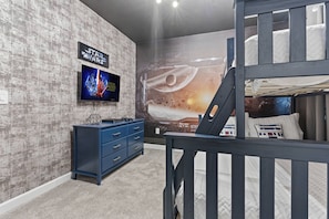 A room with a bunk bed, a Star Wars-themed wall mural, a TV, and a blue dresser. - Last Minute Disney! Private Pool, Hot Tub & Themed Bedrooms. Book Now! #93351 (Orlando)