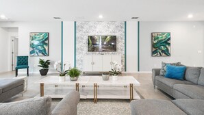 A modern living room with a marble coffee table, grey sofas, and decorative plants. - Last Minute Disney! Private Pool, Hot Tub, Game Room & Themed Bedrooms. Book Now! #103381 (Orlando)