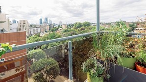 A balcony with potted plants, a cityscape view, and a clear sky. - Central Location Flat near Old St and Dalston Overlooking Rosemary Park and Regents Canal - Pass the Keys (London)