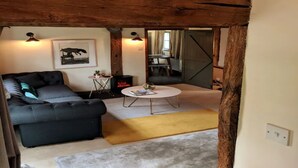 Una sala acogedora con un sofá gris oscuro, una mesita redonda y una chimenea.