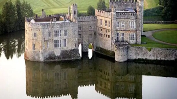 Un castillo con foso que se refleja en sus aguas.