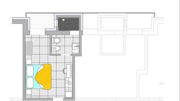 A floor plan of a hotel room with a bathroom, a kitchen area, and a living space with a sofa and a coffee table.