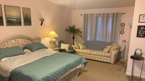 Un dormitorio con dos camas, un sofá, una lámpara y una ventana con cortinas.