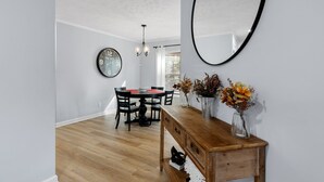 Un comedor con una mesa de madera, sillas y un reloj de pared.