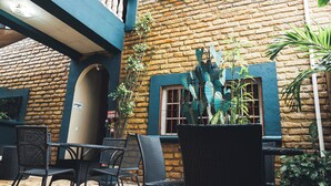 An outdoor patio area with stone flooring, wicker furniture, and potted plants.