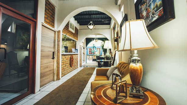 A hallway with a sofa, a lamp, and a dining area in the background.