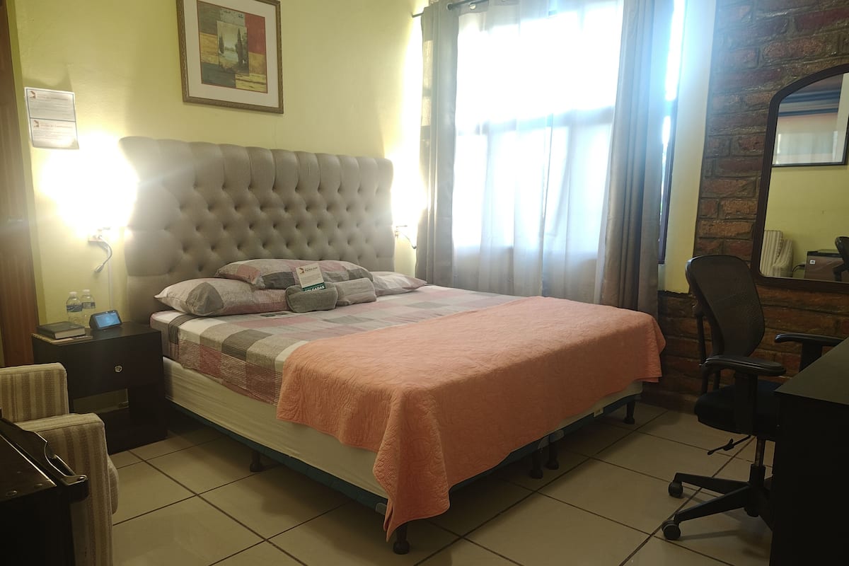 Een keurig opgemaakte hotelkamer met een groot bed, een bureau en een stoel.