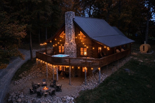 Discover your woodland retreat: a stunning Hocking Hills cabin nestled in lush greenery, featuring a spacious deck and rustic stone accents.