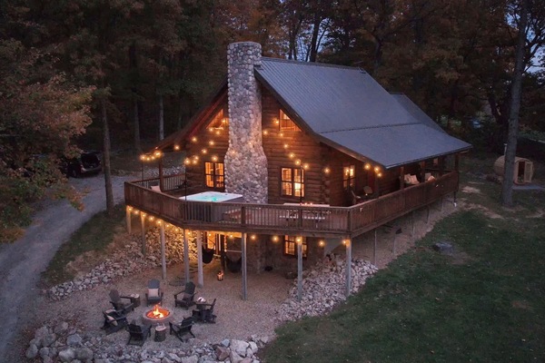 Discover your woodland retreat: a stunning Hocking Hills cabin nestled in lush greenery, featuring a spacious deck and rustic stone accents.