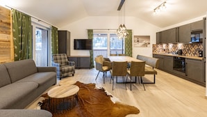 Ein modernes Wohnzimmer mit einer Couch, einem Esstisch, Stühlen und einem Fernseher.