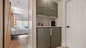 Una cucina moderna con mobili grigi, un piano di lavoro bianco e una porta bianca.