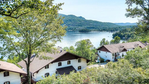 Un villaggio sul lago con case tradizionali, vista limpida sul lago e colline circostanti.