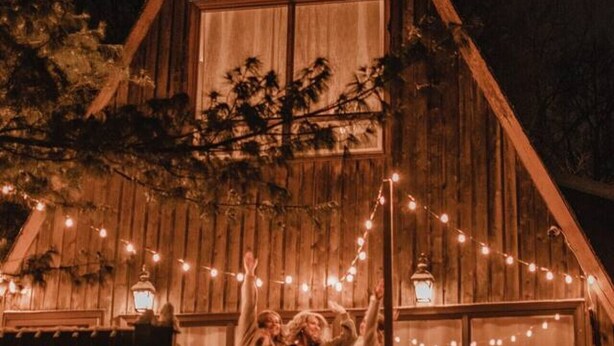 A wooden cabin with a balcony, string lights, and lanterns.