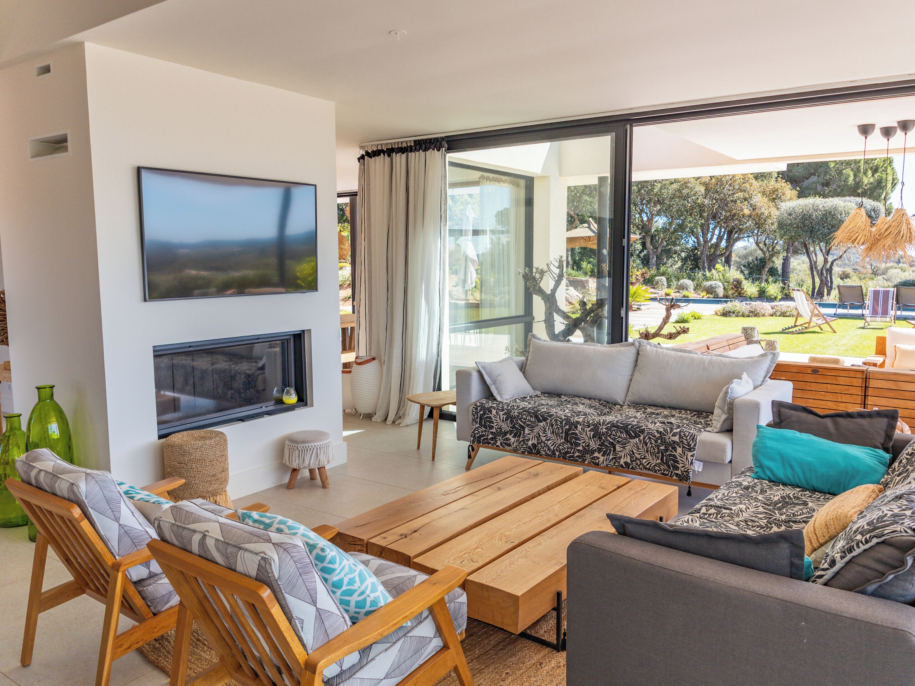 A modern living room with a large TV, comfortable seating, and a view of the outdoors.