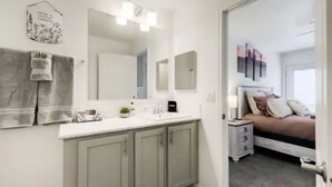 A modern bathroom with a double sink, vanity, and a large mirror. There is a towel rack and a small plant on the counter. - Cozy Mountain Town Farmhouse for Winter Fun in Flag!  (Flagstaff)