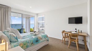 Un dormitorio con cama, escritorio y televisor.